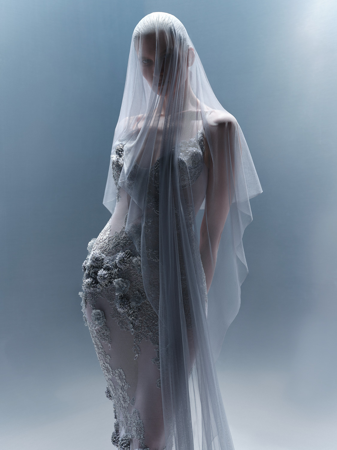 Belik — model in 3D-embroidered gown with sheer veil, blue-grey background